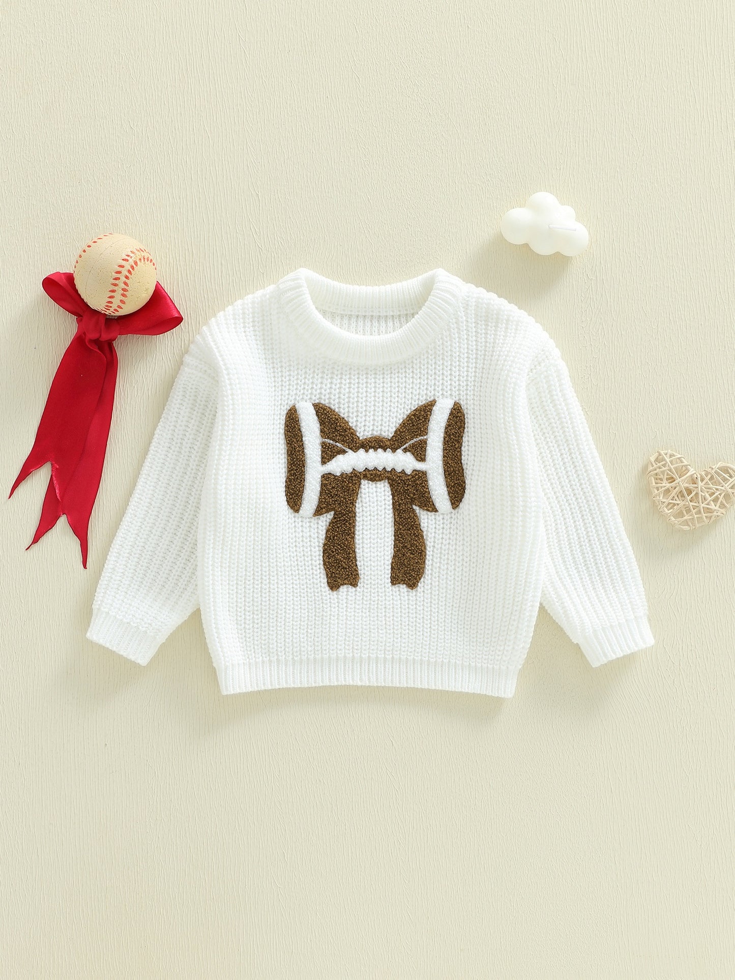 White sweater with brown bear design on a beige background